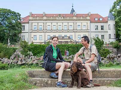 Paar macht Wanderpause vor dem Schloss Wiesenburg