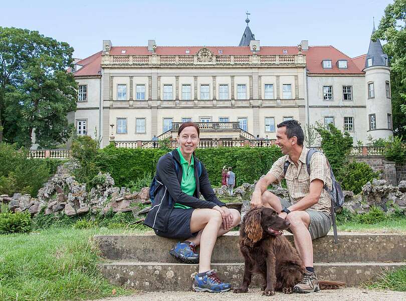 Paar macht Wanderpause vor dem Schloss Wiesenburg