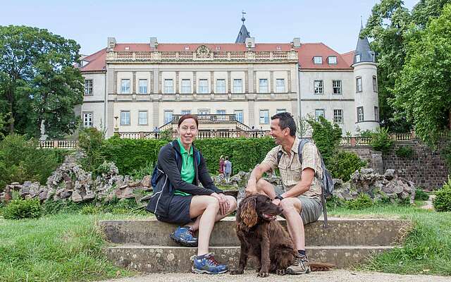 Paar macht Wanderpause vor dem Schloss Wiesenburg