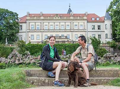 Paar macht Wanderpause vor dem Schloss Wiesenburg