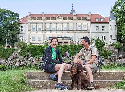 Paar macht Wanderpause vor dem Schloss Wiesenburg